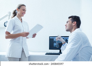 Side view of male and female dentists discussing reports