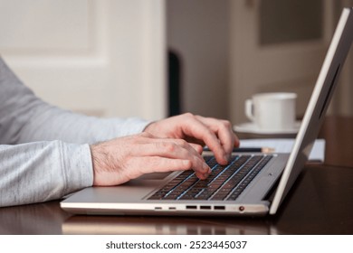 Side view of male hands writing with pen on paper and using laptop. Modern remote work and business. Typing finger on keyboard. - Powered by Shutterstock