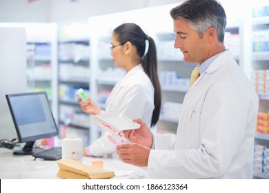 Side view of a male pharmacist counting and dispensing medications at a pharmacy counter. - Powered by Shutterstock