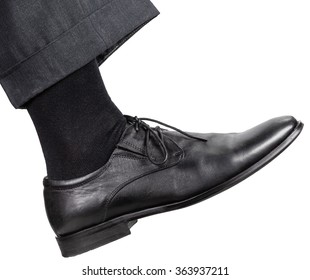 Side View Of Male Right Leg In Black Shoe Takes A Step Isolated On White Background