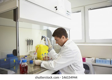 Side View Of A Male Scientist Filling Test Tube With Hitech Pipette In Laboratory