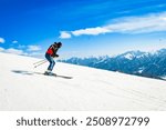 Side view male skier wear black isolated on piste ski downhill fast motion in Alps. Active winter holidays, skiing downhill in overcast day. Ski rides on the track with swirls of fresh snow