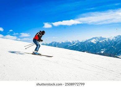 Side view male skier wear black isolated on piste ski downhill fast motion in Alps. Active winter holidays, skiing downhill in overcast day. Ski rides on the track with swirls of fresh snow