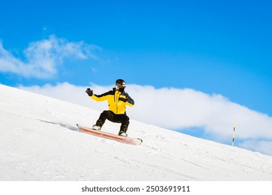 Side view male snowboarder wear yellow black on piste ski downhill fast motion in Alps. Active winter holidays, skiing downhill in overcast day. Ski rides on the track with swirls of fresh snow