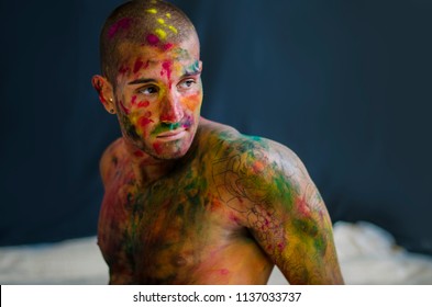 Side view of man, face painted with holi color powders.On dark background. Close-up.