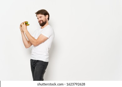 Side view of a man holding a hamburger in his hands