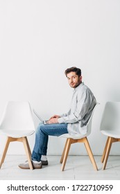 Side view of man with laptop sitting on chair while waiting for job interview - Shutterstock ID 1722710959