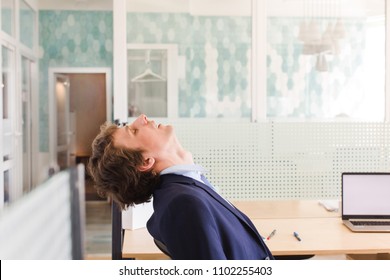 Side view of man leaning back in chair with eyes closed and masturbating at work dreaming of erotic scenes