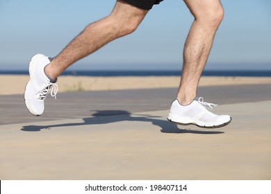 Side View Of A Man Legs Running On The Beach Seafront With The Sky In The Background