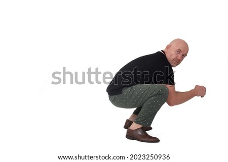 side view of a man looking at camera and sitting squatting on white background