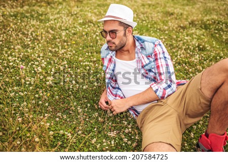 side view of a man lying down on a field and thinks 
