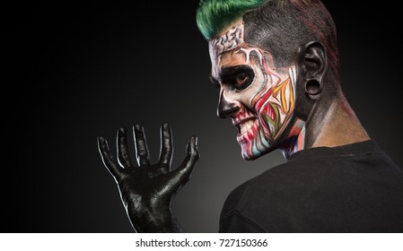 Side view of a man with monster face make up and hand painted in black. Mystical face art, man with skull makeup.