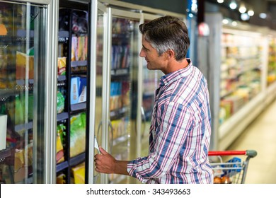 Side View Of Man Opening Supermarket Fridge