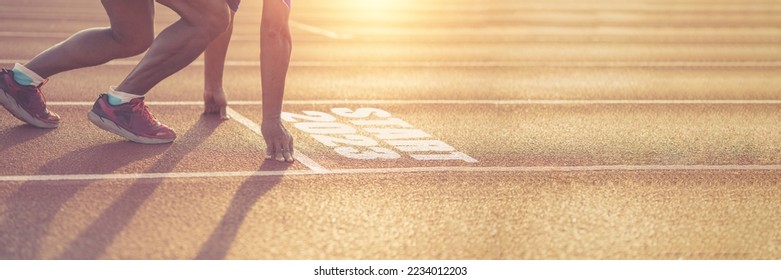 Side view of a man preparing to run on an athletics track. Engraved year 2023 symbolizing the beginning of the new year. Achievement goals get ready for the new year.