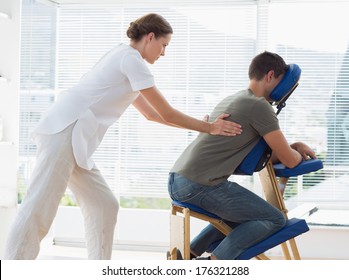 Side view of man receiving back massage from physiotherapist in hospital