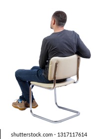 Side View Of A Man Sitting On A Chair. Rear View People Collection.  Backside View Of Person.  Isolated Over White Background. Stylish Guy In Boots Sits On A White Chair.