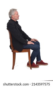 Side View Of A Man Sitting  On Chair With Sneakers Jeans And Blazer On White Background