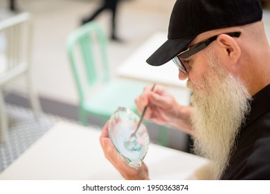 Side View Of Man Sitting In Shopping Mall And Eating Ice Cream