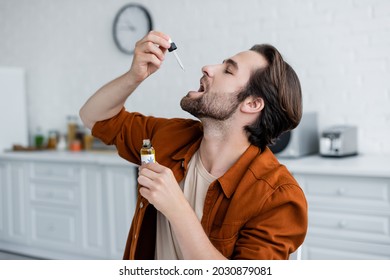 Side view of man taking cbd oil at home