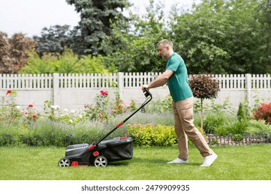 Side view of man using lawn mower cutting the grass in the backyard. Modern agricultural machinery for the care of the garden