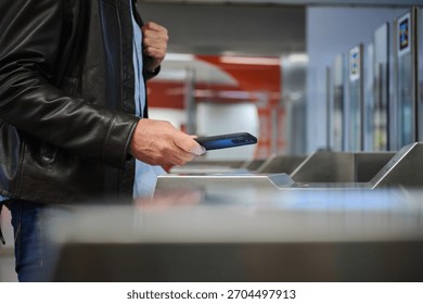 side view of a Man using mobile phone for contactless payment at a public transport entrance