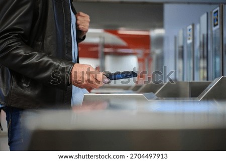 side view of a Man using mobile phone for contactless payment at a public transport entrance