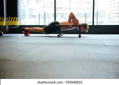 Side view of man which doing push-ups in gym with window on background