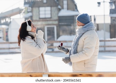 Side View Of Man In Winter Hat Holding Box With Wedding Ring Near Young Woman With Closed Eyes