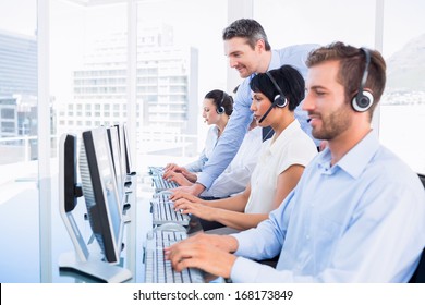 Side view of manager and executives with headsets using computers in the office