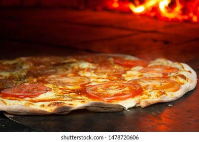 Side View Of Marguerita Pizza On A Brick Pizza Oven. Pizza Marguerita On The Table.