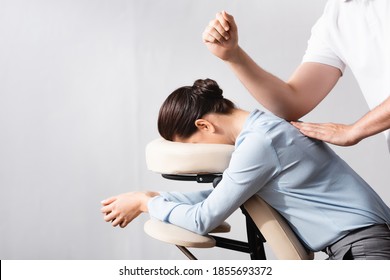 Side view of masseur massaging woman back with elbow, sitting on massage chair on white background - Powered by Shutterstock