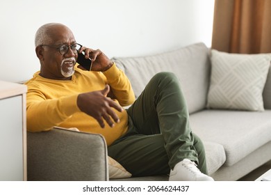 Side View Of Mature Black Male Talking On Smartphone Communicating Sitting On Couch Indoor, Looking Aside. Senior Man Chatting Having Phone Conversation. Mobile Communication Concept - Powered by Shutterstock