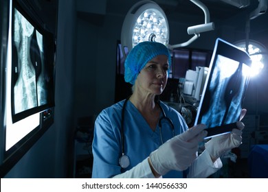 Side view of mature Caucasian female surgeon examining x-ray in operating room of hospital - Powered by Shutterstock