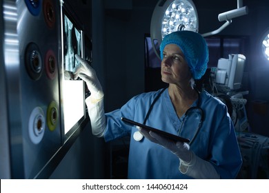 Side view of mature Caucasian female surgeon examining x-ray on light box in operating room of hospital - Powered by Shutterstock