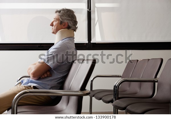 Side view of mature man with neck brace waiting in\
hospital lobby