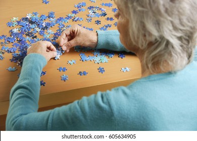 Side View Of Mature Woman Doing Puzzle.