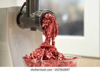  Side view of a meat grinder and minced meat falling into a glass bowl. Selective focus.                              