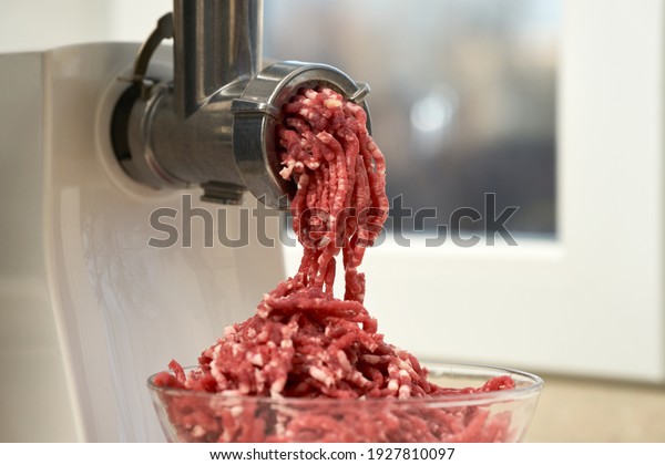 
Side view of a meat grinder and minced meat falling into a glass
bowl. Selective focus.                             
