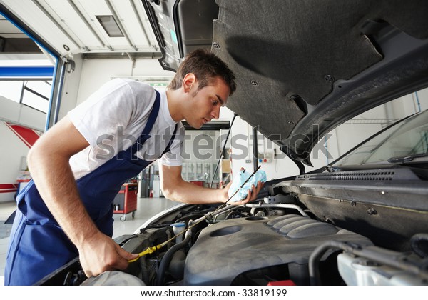 side view of mechanic\
checking motor oil