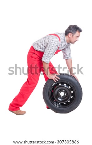Side view of a mechanic pushing a new car wheel isolated on white