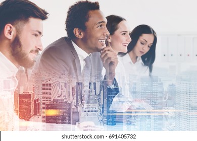 Side View Of Members Of A Business Team Sitting Together At A Table And Looking At A Person Off Camera And Listening To Them. Cityscape. Mock Up Toned Image Double Exposure