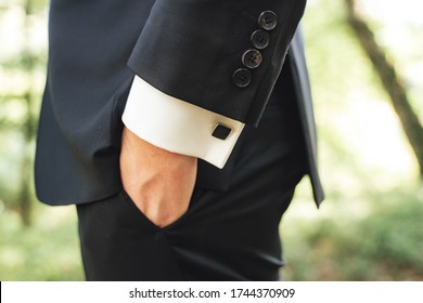 Side View Of Men In Black Suit. Close Up Of Hand In Pocket. Black Square Cufflinks On White Shirt Sleeves. Outdoor Background.