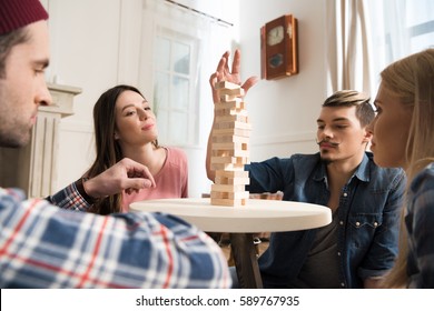 Side View Of Men And Women Playing Jenga Game At Home