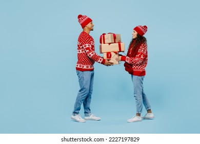 Side view merry young couple two man woman wear red Christmas sweater Santa hat posing hold pile present box with gift ribbon bow isolated on plain blue background. Happy New Year 2023 holiday concept - Powered by Shutterstock