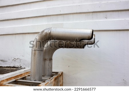 side view of metal chimney with two holes in roof of building