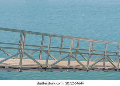 Side View Of Metal Gang Plank Over Ocean Water At Seaport.