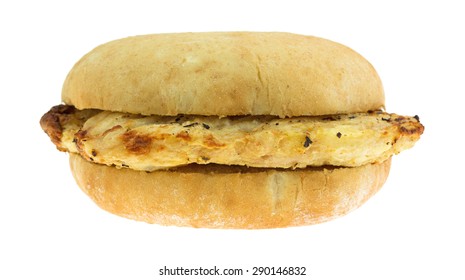 Side View Of A Microwaved Previously Grilled Chicken Breast Sandwich On A White Bread Bun Isolated On A White Background.