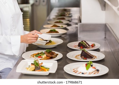 Side view mid section of a female chef garnishing food in the kitchen