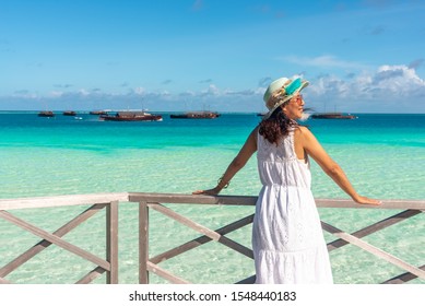 Side View Of Middle Aged Asian Woman Tourist In White Dress Standing And Relaxing On The Terrace And See Beautiful Turquoise Sea  In Vacation Time At Maldives.