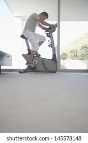 Side View Of Middle Aged Man Using Exercise Bike At Home